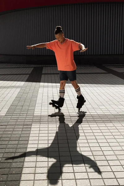 Sorrindo patinador de rolo em roupas casuais fazendo truque na rua urbana — Fotografia de Stock