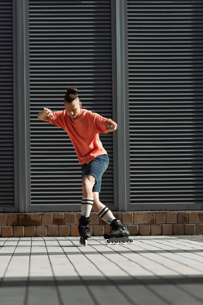 Homem de roupas casuais e lâminas de rolo andando na rua urbana — Fotografia de Stock
