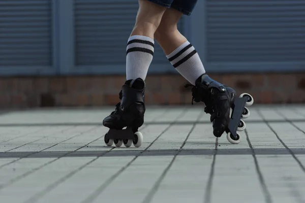 Vista recortada del patinador en calcetines de rodilla y patines montados en la calle - foto de stock