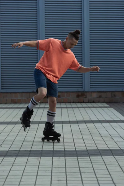Молодой человек в роликовых коньках и шортах катается на природе — стоковое фото