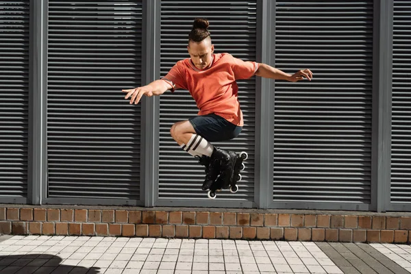 Орієнтований чоловік в роликових лезах робить трюк на міській вулиці — стокове фото