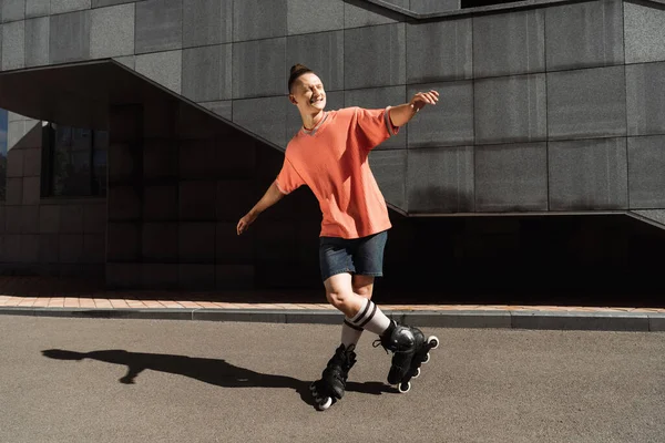 Joven alegre en patines de pie sobre asfalto en la calle - foto de stock