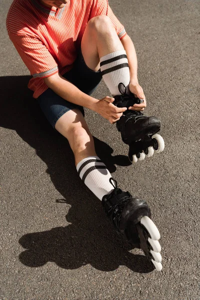 Vista ritagliata dell'uomo in pantaloncini che indossa lame a rullo su asfalto — Foto stock