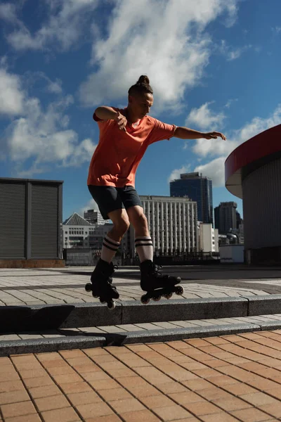 Patinador de rolo elegante pulando de escadas enquanto fazendo truque na rua urbana — Fotografia de Stock