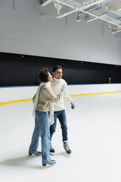 Jeune femme afro-américaine patinage sur glace tout en passant du temps avec son petit ami sur la patinoire — Photo de stock