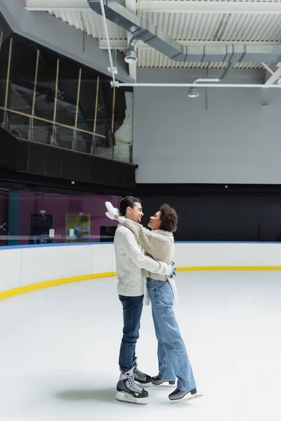 Side view of african american woman embracing boyfriend on ice rink — Stock Photo