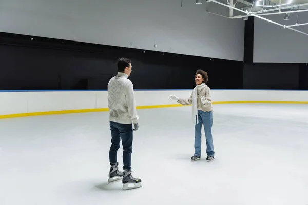 Mujer afroamericana hablando con su novio mientras patina en pista de hielo - foto de stock