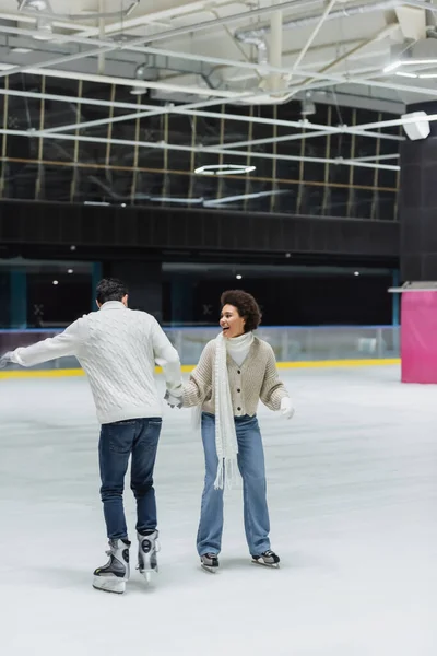 Feliz mulher afro-americana patinação no gelo com namorado no ringue — Fotografia de Stock