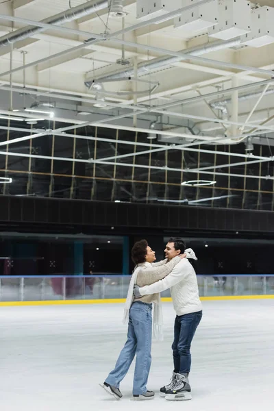 Side view of cheerful african american woman embracing boyfriend on ice rink — Stock Photo