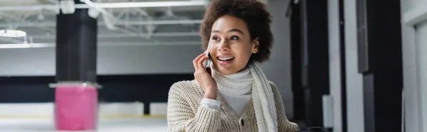 African american woman in warm clothes talking on smartphone on ice rink, banner — Stock Photo