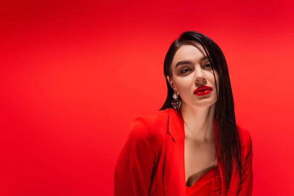 Портрет элегантной женщины в куртке, смотрящей в камеру, изолированную на красном — стоковое фото