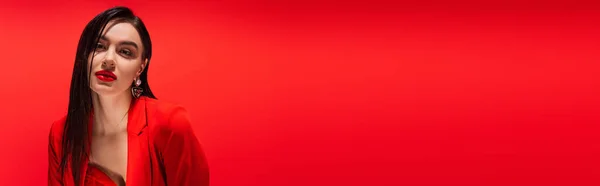 Porträt einer jungen brünetten Frau in Jacke, die auf rotem Banner isoliert in die Kamera blickt — Stockfoto