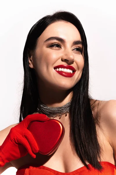 Portrait of pretty brunette woman with red lips holding heart shaped gift box isolated on white — Stock Photo