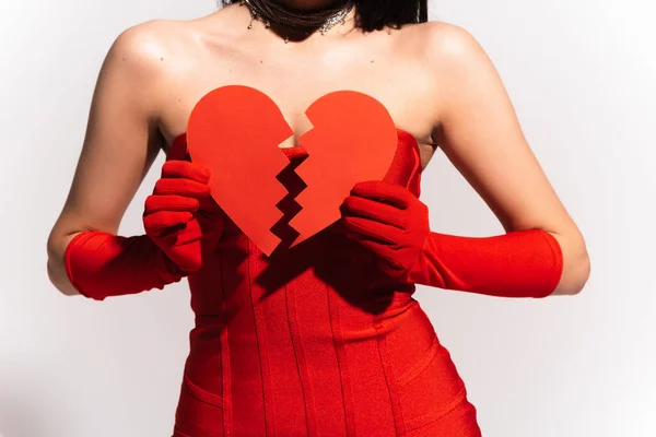 Обрезанный вид стильной женщины в красных перчатках с разбитым бумажным сердцем на сером фоне — стоковое фото