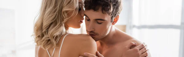 Young man kissing shoulder of blonde girlfriend at home, banner — Stock Photo