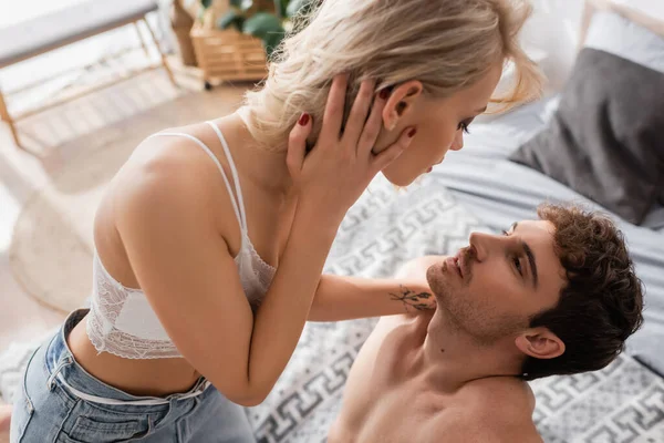 Vista ad alto angolo della donna bionda sexy che tocca il fidanzato sul letto — Foto stock