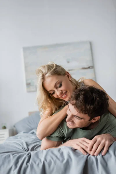 Schöne blonde Frau umarmt Freund morgens im Pyjama auf dem Bett — Stockfoto