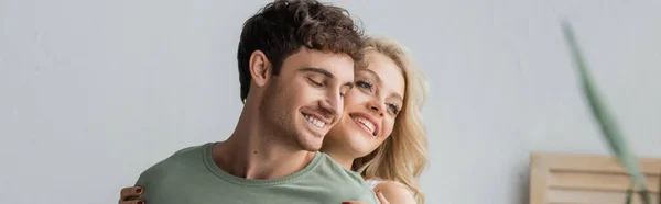 Jeune femme blonde étreignant heureux petit ami à la maison le matin, bannière — Photo de stock