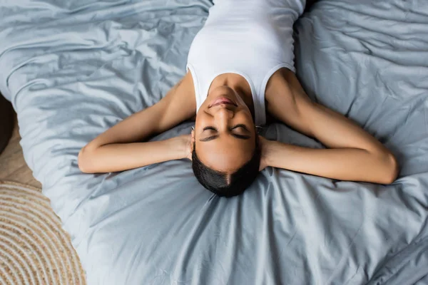 Высокий угол зрения на молодую африканскую американку лежащую на кровати дома — стоковое фото