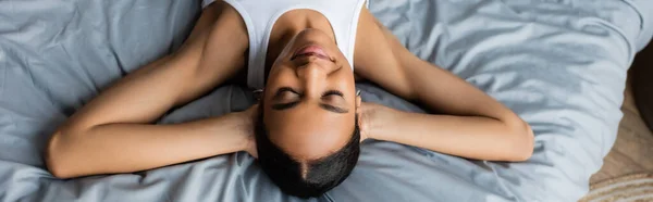 Vista ad alto angolo di giovane donna afroamericana sdraiata sul letto a casa, banner — Foto stock