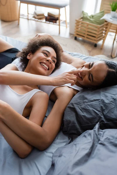 Lesbian african american woman touching nose of happy girlfriend in bedroom — Stock Photo