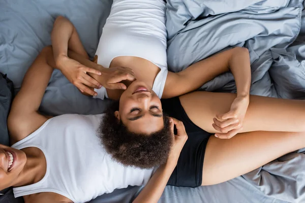 Vista superior da mulher americana africana encaracolado deitado na barriga da namorada — Fotografia de Stock