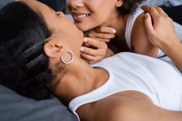 Heureux lesbienne afro-américain couple câlin tandis que couché sur le lit — Photo de stock