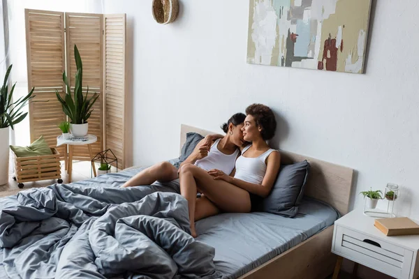 Junge lesbische Afroamerikanerin umarmt Freundin im modernen Schlafzimmer — Stockfoto
