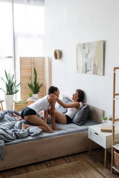 Glücklich lesbische afrikanisch-amerikanische Frau umarmt junge Freundin in modernen Schlafzimmer — Stockfoto
