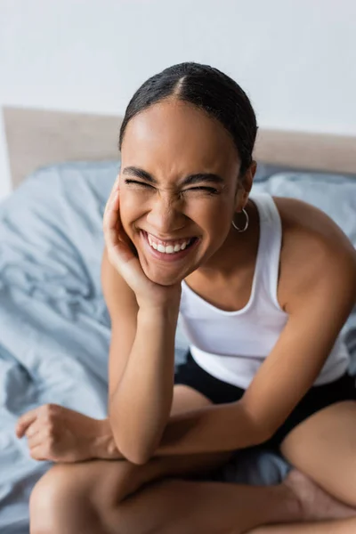 Retrato de mujer afroamericana feliz con los ojos cerrados sonriendo en el dormitorio - foto de stock