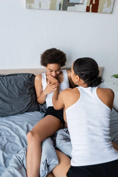 Lesbian african american woman touching cheek of curly girlfriend in modern bedroom — Stock Photo