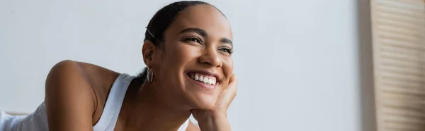 Portrait de heureuse femme afro-américaine souriante et regardant loin dans la chambre, bannière — Photo de stock
