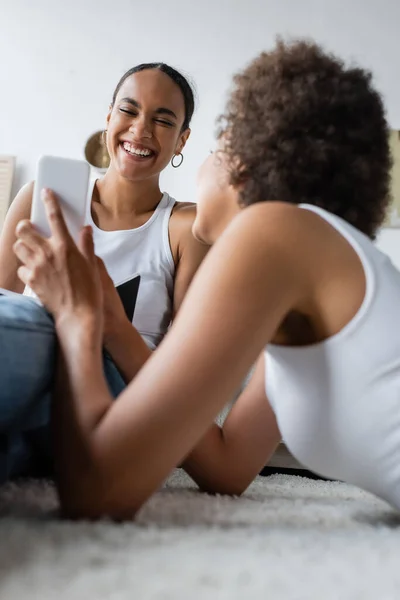 Encaracolado Africano americano mulher mostrando smartphone para alegre namorada — Fotografia de Stock