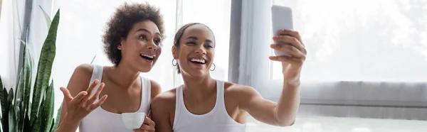 Heureux afro-américain lesbienne femme prendre selfie avec petite amie tenant tasse de café, bannière — Photo de stock