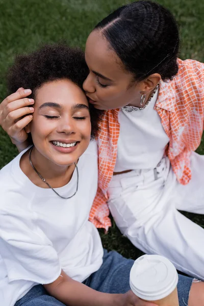 Top view of african american lesbian woman kissing head of happy girlfriend in park — Stock Photo