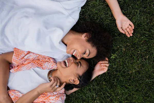 Vista superior de las alegres mujeres lesbianas afroamericanas tumbadas en la hierba - foto de stock