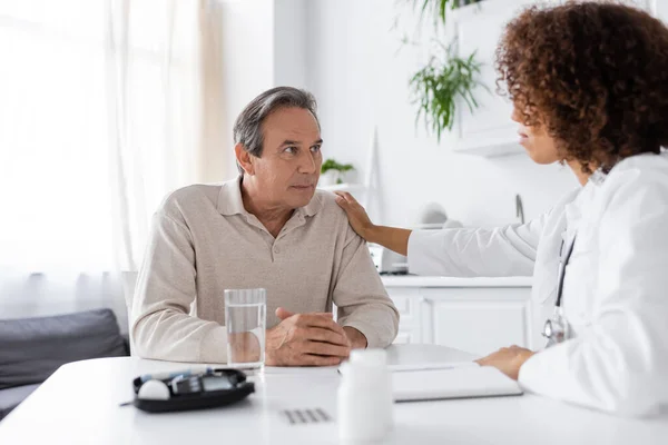 Curly african american doctor calming middle aged man with diabetes — Stock Photo