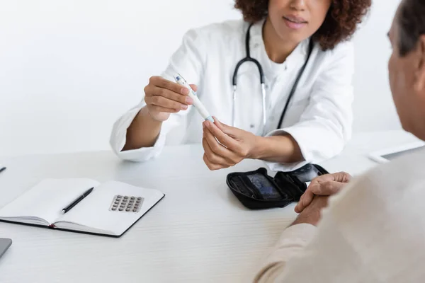 Cropped view of african american doctor holding lancet pen near middle aged patient with diabetes in clinic — Stock Photo