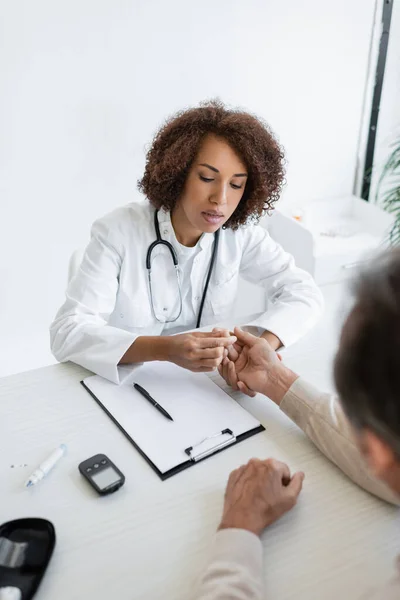 Médecin afro-américain vérifiant la main d'un patient flou diabétique en clinique — Photo de stock