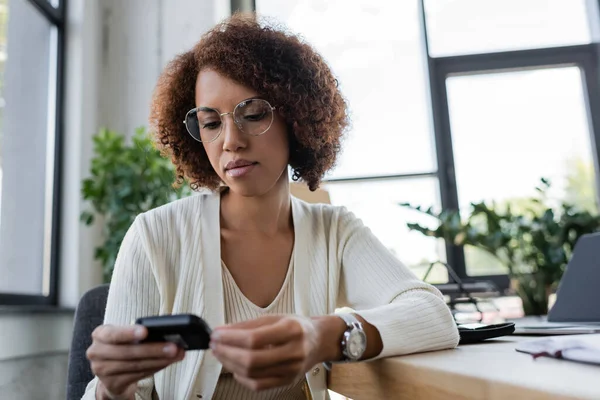 Young african american businesswoman looking at blurred glucometer in office — Stock Photo