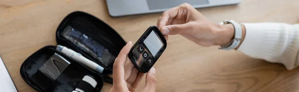 Cropped view of african american businesswoman with diabetes using glucometer in office, banner — Stock Photo