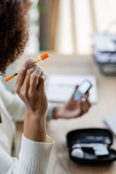 Обрезанный взгляд на африканскую американскую деловую женщину с диабетом, держащую шприц в офисе — стоковое фото
