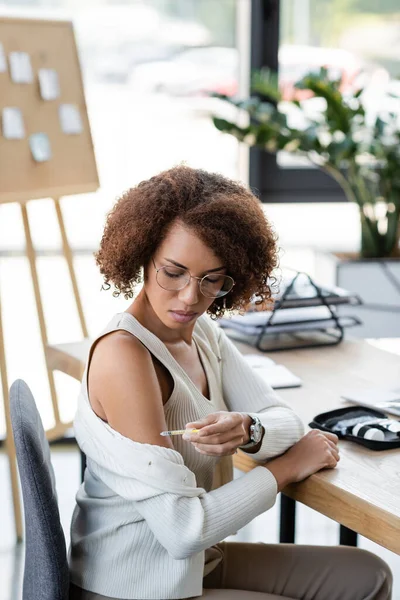 African american businesswoman with diabetes doing insulin injection in office — Stock Photo