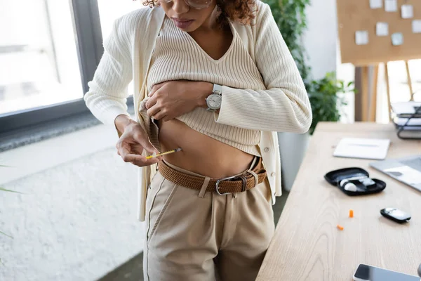 Cropped view of african american businesswoman doing insulin injection near blurred diabetes kit in office — Stock Photo