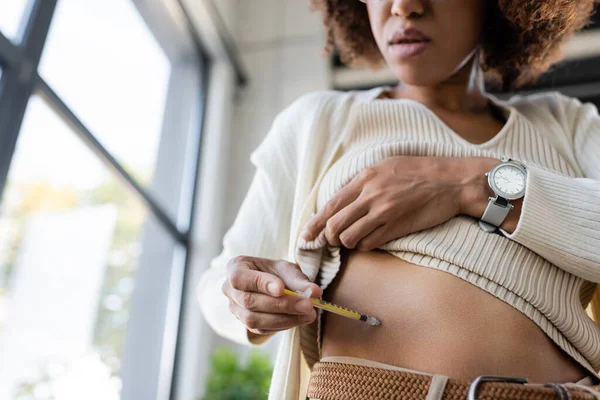 Vue à angle bas d'une femme d'affaires afro-américaine faisant une injection d'insuline dans le corps au bureau — Photo de stock