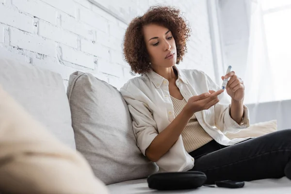 African american woman with diabetes using lancet pen at home — Stock Photo