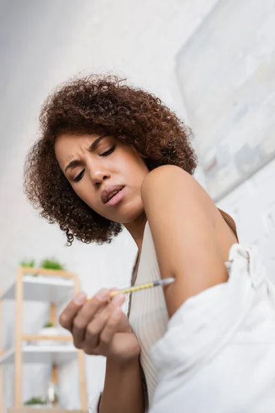 Low angle view of african american woman with diabetes feeling pain while doing insulin injection at home — Stock Photo