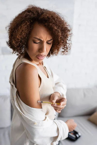 Afro-americana com diabetes sentindo dor ao fazer injeção de insulina no braço em casa — Fotografia de Stock