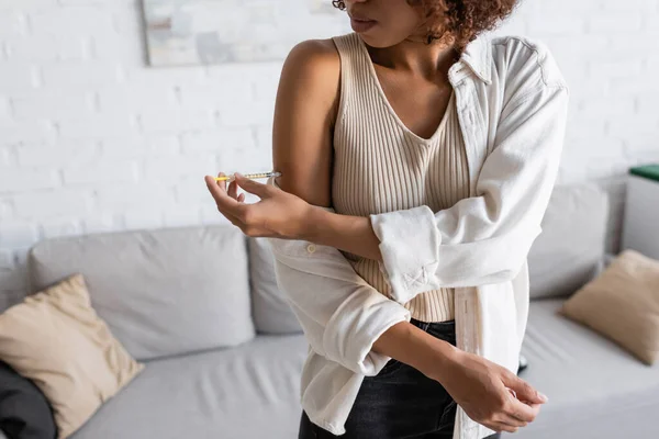 Обрезанный вид африканской американки, делающей инъекции инсулина в руке дома — стоковое фото