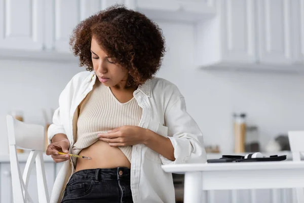 African american woman with diabetes doing insulin injection in kitchen — Stock Photo